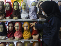 An Indonesian Muslim woman wearing face mask looking for headscarves at a hijab shop in Bogor on April 26, 2021, during the Muslim holy fast...