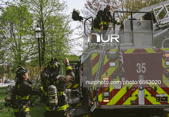 A fire fighter throws his helmet and other gear to fire fighters on the ground, of the Historic House In Palmer Square, Chicago, USA, on Apr...