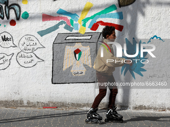 A Palestinian boy roller-skate past a mural painting calling on people to vote during the upcoming elections (legislative in May and preside...