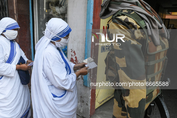 A sister of Missionaries of Charity shows her Voter ID card to a CRPF personal before she is allowed inside a polling station in Kolkata , I...
