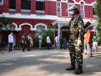 A Women paramilitary personnel stand and Voters stand in a line to cast their vote at a polling station during  8th phase of West Bengal ass...