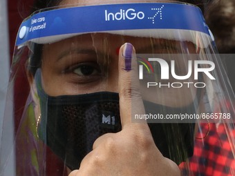 A Women warring Protective Facemask and Face Shield shows her finger after casting her vote outside a polling station during  8th phase of W...