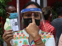 A Women warring Protective Facemask and Face Shield shows her finger after casting her vote outside a polling station during  8th phase of W...