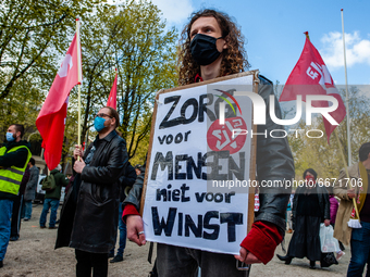 A man is holding a placard asking to take care of the workers, during the International Worker's Day demonstration held in Amsterdam, on May...