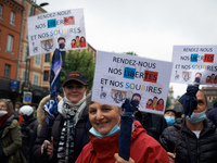 People hold placards reading 'Give us back our freedoms and our smiles'. Thousands of people took to the streets for Labour Day in Toulouse....