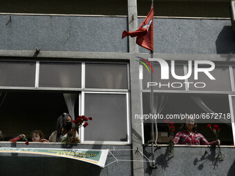 People from a building's windows watch and cheer on the participants of the Labor Day March. Lisbon, May 01, 2021. Hundreds of people partic...