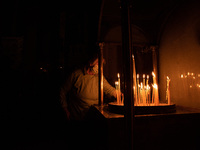 An old lady is lighting a candle at Agios Spyridonas church in Pagkrati, a central neighborhoud of Athens.  On May 1, 2021 in Athens, Greece...