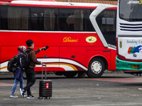 Passengers walks towards bus to return to their hometowns known locally as 