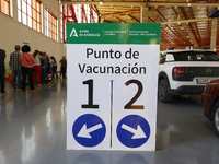 A vaccination point sign and queues of people and cars during the mass covid-19 vaccination campaign with the AstraZeneca and Comirnaty (Pfi...