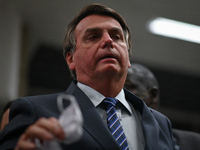 Brazil's President Jair Bolsonaro speaks to journalists holding a protective face mask on hands during a press conference amidst the Coronav...