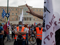 Member of the builders union wearing protective masks and helmets hold flags, as the they protest during a rally commemorating May day in At...