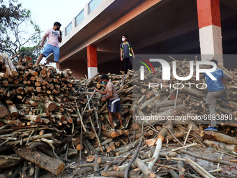 Relatives sort wood from a pile during the cremation of a person, who died due to the coronavirus disease (COVID-19), at a makeshift cremato...