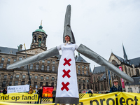 A woman is dressing like a mega wind turbine while surrounded by huge yellow banners at the Dam square, during the national demonstration ag...