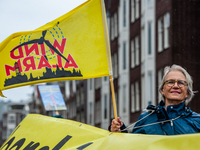 People are walking with huge yellow banners and placards to the Westerpark, during the national demonstration against wind turbines near hom...