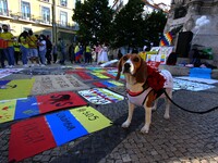 A dog poses near posters condemning the violence in Colombia during a rally in Luis de Camões square, Lisbon. 08 May 2021. Colombians in Por...