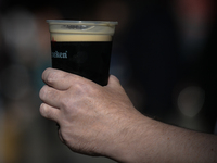 A person holds a pint of Guinness in a plastic cup on the street in Dublin's city center during the final days of the COVID-19 lockdown. 
On...