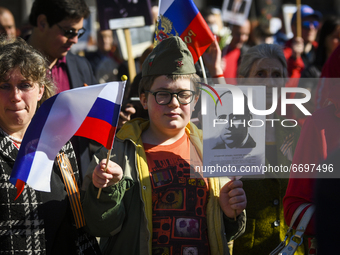 Boy holds portrait and waves Russian flag  during so-called Immortal Regiment procession - celebration of Victory Day, to commemorate the 76...
