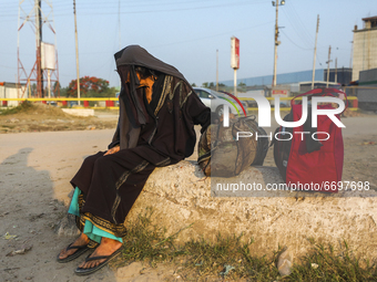 an elderly woman waits for a ferry as she wants to travel back home ahead of the Muslim festival Eid al-Fitr at Shimulia ferry ghat in Munsh...