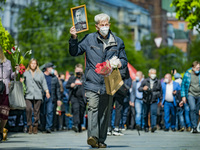 A man show a portrait of a soldier relative in the Second World War during the remembrance of the Victory Day on May 9th in the Eternal Flam...