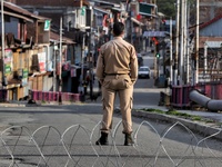 An Indian Policeman (JKP Cop) is seen at a temporary check point during COVID-19 Corona Curfew in Baramulla, Jammu and Kashmir, India on 09...