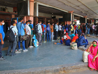 Passengers stand in a queue at a ticket counter to board buses for their native place, after authorities announced 14 Days lockdown , amid s...
