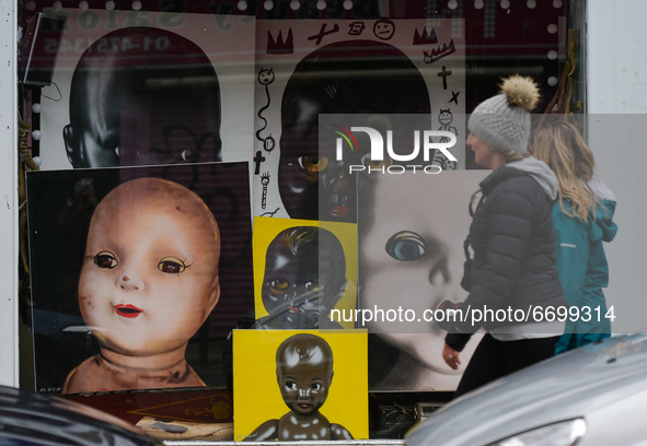 Two women walk by images of children seen in the window of a closed Art Gallery in Dublin city center during the final days of the COVID-19...