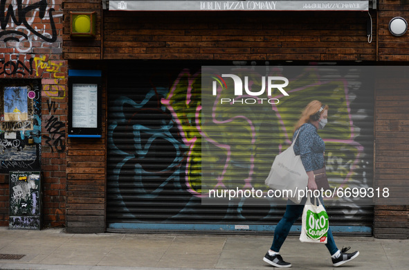 A woman wearing a face mask walks past a closed pizza restaurant in Dublin city center, during the final days of the COVID-19 lockdown. 
On...