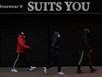 Three young men walk past by a closed Menswear 'Suits You' store in Dublin city center.
On Sunday, 9 May 2021, in Dublin, Ireland. (