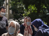 An Iranian elderly woman wearing a protective face mask looks on as she arrives a heath center for receiving a dose of China's Sinopharm new...