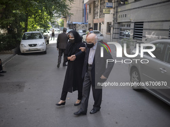 An Iranian woman helps her elderly father while arriving a health center for receiving a dose of China's Sinopharm new coronavirus disease (...