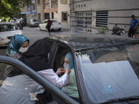 An Iranian elderly woman receives a dose of China's Sinopharm new coronavirus disease (COVID-19) vaccine while sitting in a vehicle just out...