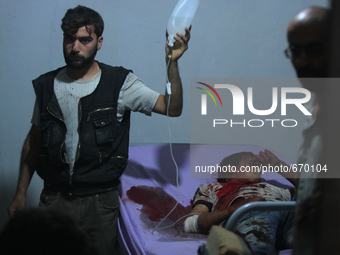 An injured man carries a serum bag for another injured civilian in a field hospital after what activists said were air strikes by forces of...