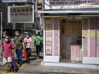 People wearing face masks walks pass a Real Estate agent  Store in Hong Kong, Monday, May 10, 2021. (