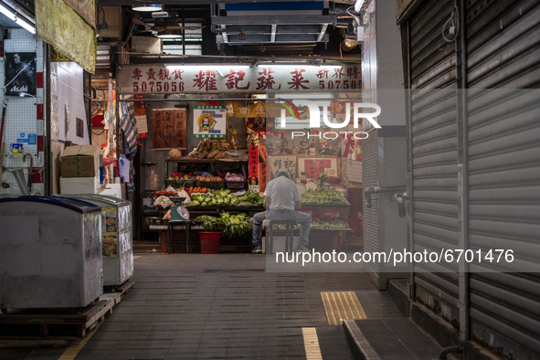 A Man sits in front of a fruit store in a wet market in Hong Kong, Monday, May 10, 2021. 