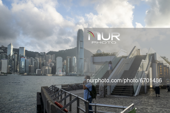 A Man talks on his phone while standing in front of the Hong Kong City Skyline in Hong Kong, Monday, May 10, 2021. 
