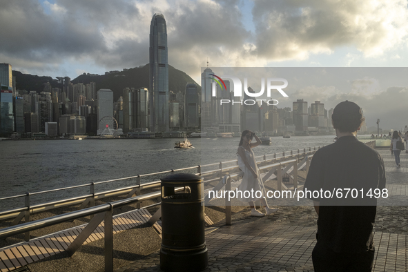 A Women pose for a photo in front the Hong Kong City Skyline in Hong Kong, Monday, May 10, 2021. 