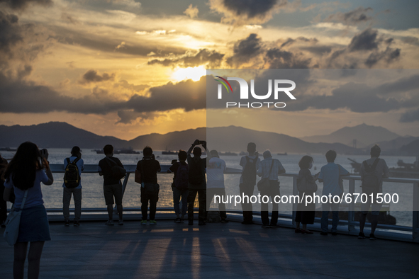 People take photos of the sunset in Hong Kong, Monday, May 10, 2021. 