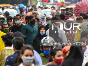 A girl is seen wearing a mask improperly amidst a sea of people who flocked to shop at a market before Ramadan in Kolkata , India , on 10 Ma...