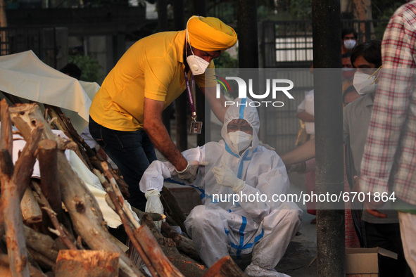 A volunteer tries to console a family member (in PPE) who breaks down during the cremation of a relative, who died due to the coronavirus di...