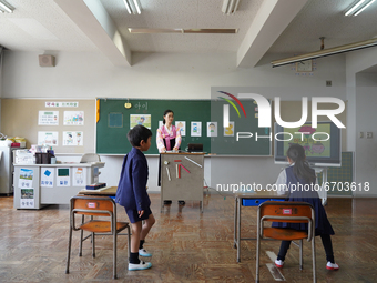 Two elementary students stand up as a teacher wearing a traditional dress closes a Korean lesson at Hiroshima Korean School on May 9, 2021 i...