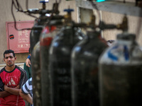 Workers fill in the oxygen cylinders used for Covid-19 patients before they are sent to hospitals and citizens buy them for isolation patien...