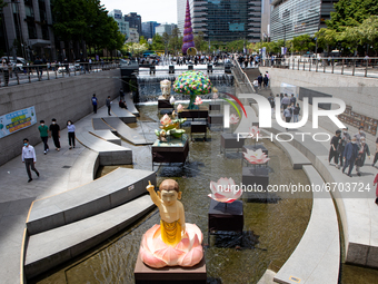 Office workers take a rest during a sunny day near lanterns displayed for the upcoming celebration of Vesak day at the Cheonggyecheon stream...