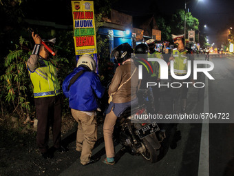 Indonesian Police officers stand at a checkpoint to return the motorist as Indonesian authorities ban annual mass migration, known as 'Mudik...