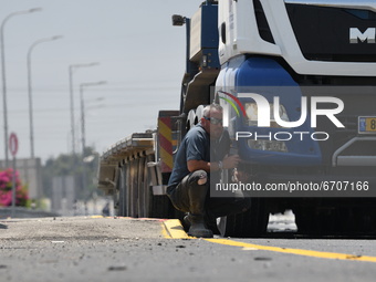 Israeli truck driver takes a shelter near his truck as a siren alerting of incoming rockets fired from Gaza Strip, is heard on May 12, 2021...