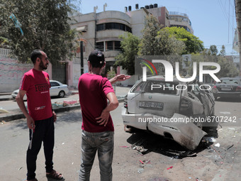 People inspect a car that was hit in an Israeli airstrike that killed three people in the car, on the main road in Gaza City, Wednesday, May...