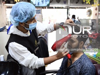 A salon staff wearing a protective suit and facemask is seen serve his clients in a salon at Rampura in Dhaka, Bangladesh on May 12, 2021 am...