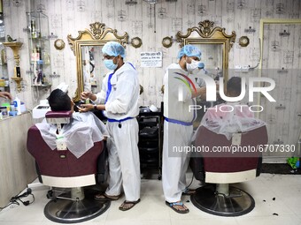 Barbers wearing personal protective equipment serve their clients in a salon at Rampura in Dhaka, Bangladesh on May 12, 2021 amid the corona...