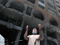 A Palestinian man walks at the rubble of the severely damaged Al-Jawhara Tower in Gaza City on May 12, 2021 after it was hit by Israeli airs...