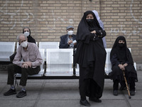 Iranian elderly men and women wearing protective face masks look on as they wait to receive a dose of the new coronavirus disease (COVID-19)...