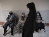 Iranian elderly women wearing protective face masks sit at a corridor while waiting to receive a dose of the China's Sinopharm new coronavir...